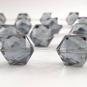 May include: A strand of gray faceted glass beads, strung on clear thread. The beads are hexagonal in shape and have a shiny, reflective surface.