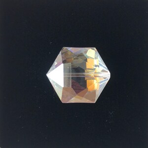 May include: A clear glass crystal bead with a faceted design. The bead has a hexagonal shape and is iridescent.