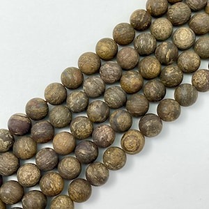 May include: A strand of brown and gray gemstone beads. The beads are round and have a natural, rough texture.