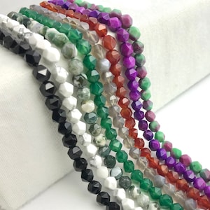 May include: A collection of faceted gemstone beads in various colors, including black, white, green, red, purple, and gray. The beads are strung together, showcasing their geometric shapes and natural variations. Ideal for jewelry making.