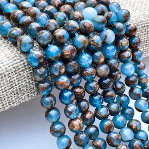 May include: A strand of blue and gold gemstone beads. The beads are round and have a marbled appearance.