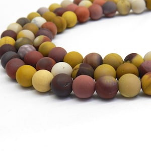 May include: A strand of colorful gemstone beads, featuring shades of red, brown, yellow, and white. The beads are round and smooth, with a matte finish.