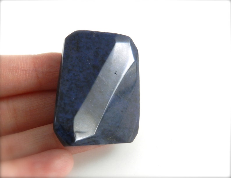 May include: A dark blue, faceted, rectangular stone with a rough, textured surface.