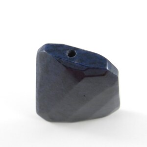May include: A dark blue faceted gemstone pendant with a hole drilled through the top for stringing.
