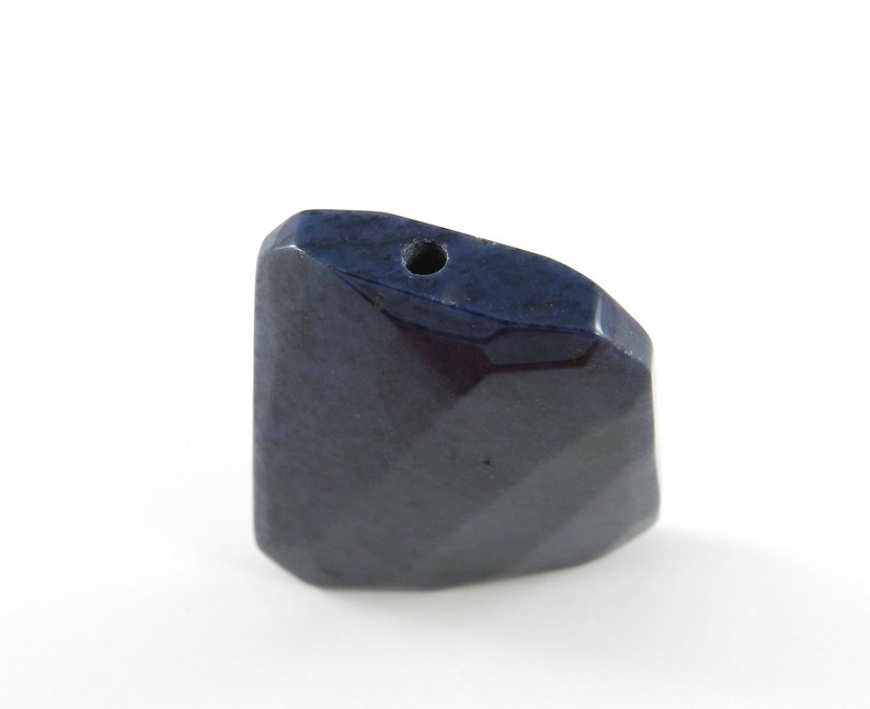 May include: A dark blue faceted gemstone pendant with a hole drilled through the top for stringing.