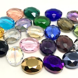 May include: Assortment of oval-shaped faceted glass beads in various colors, including clear, pink, purple, blue, green, gold, and black.