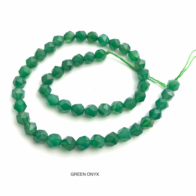 May include: A strand of faceted green onyx beads. The beads are a deep emerald green color and have a geometric shape. The string holding the beads is a light green color. The text "GREEN ONYX" is at the bottom of the image.
