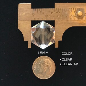 May include: A clear glass prism with a hexagonal shape, measuring 18mm in diameter. The prism is shown next to a US dime for size comparison. The text "COLOR: &bull;CLEAR &bull;CLEAR AB" is also visible in the image.