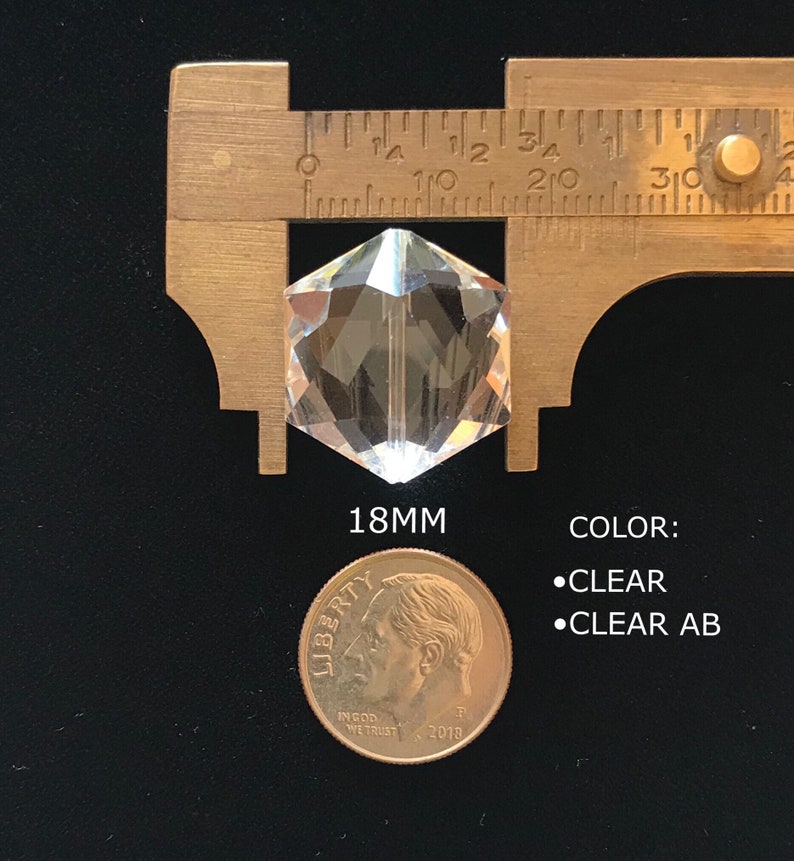 May include: A clear glass prism with a hexagonal shape, measuring 18mm in diameter. The prism is shown next to a US dime for size comparison. The text "COLOR: &bull;CLEAR &bull;CLEAR AB" is also visible in the image.