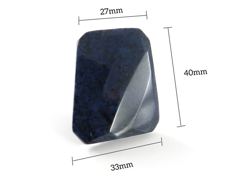May include: A dark blue, faceted, gemstone with a rough, natural texture. It measures approximately 40mm tall, 27mm wide, and 33mm deep.