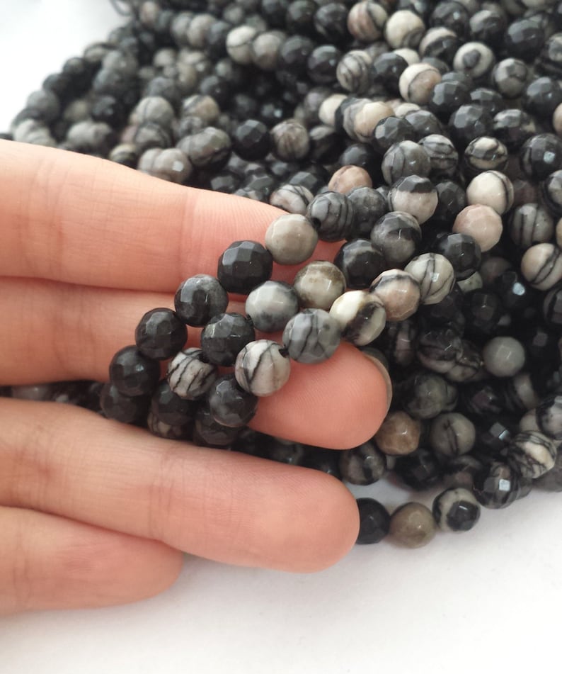 May include: A strand of black and white striped gemstone beads. The beads are faceted and have a natural, organic look.