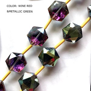 May include: A strand of faceted glass beads in wine red and metallic green colors. The beads are hexagonal in shape and are strung on yellow thread.