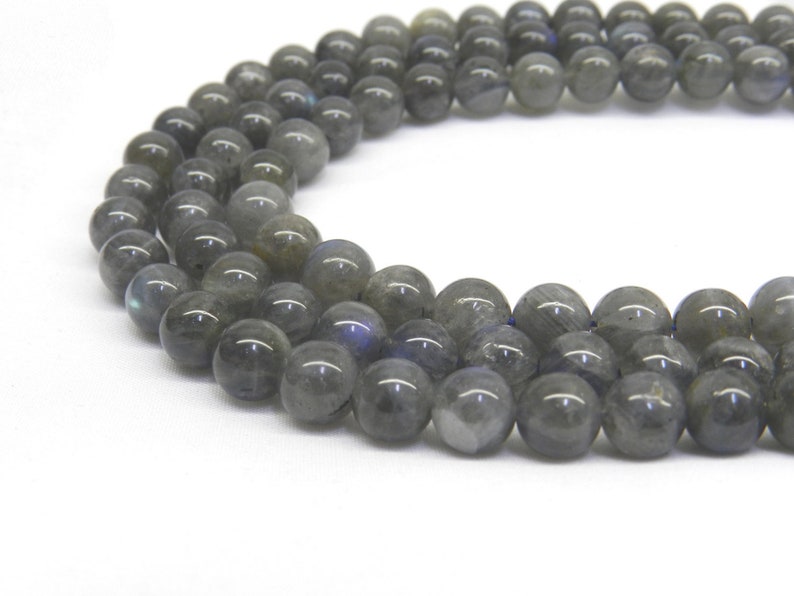 May include: A strand of dark gray labradorite gemstone beads. The beads are round and have a smooth, polished finish. The beads are strung on a clear elastic cord.