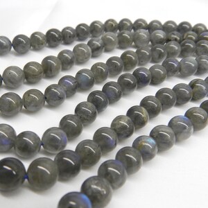 May include: A strand of round, gray labradorite beads. The beads have a slight iridescent sheen.