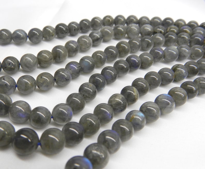 May include: A strand of round, gray labradorite beads. The beads have a slight iridescent sheen.