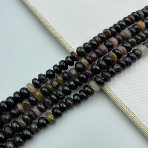 May include: A strand of black, green, and pink gemstone beads. The beads are round and have a smooth, polished finish.