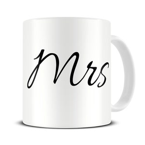 以下が含まれることがあります： 白いセラミック製のマグカップに、黒い筆記体で「Mrs.」と書いてあります