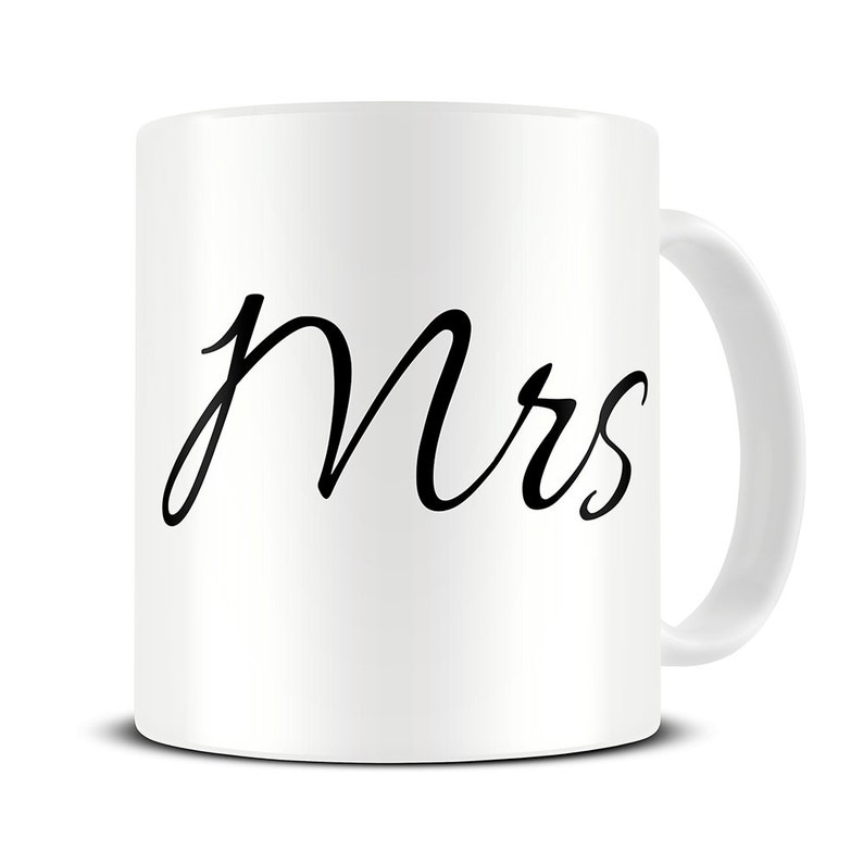 以下が含まれることがあります： 白いセラミック製のマグカップに、黒い筆記体で「Mrs.」と書いてあります