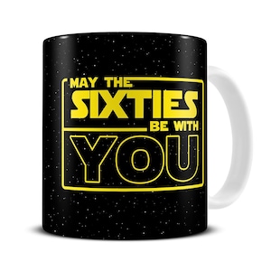May include: A black coffee mug with a white handle. The mug has a black background with white stars and a yellow rectangle with the text "May the Sixties Be With You".