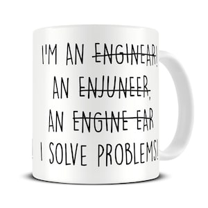 Op de afbeelding: Witte keramische mok met zwarte tekst die luidt: "Ik ben een ingenieur, een enjuneer, een engine-ear, ik los problemen op!"