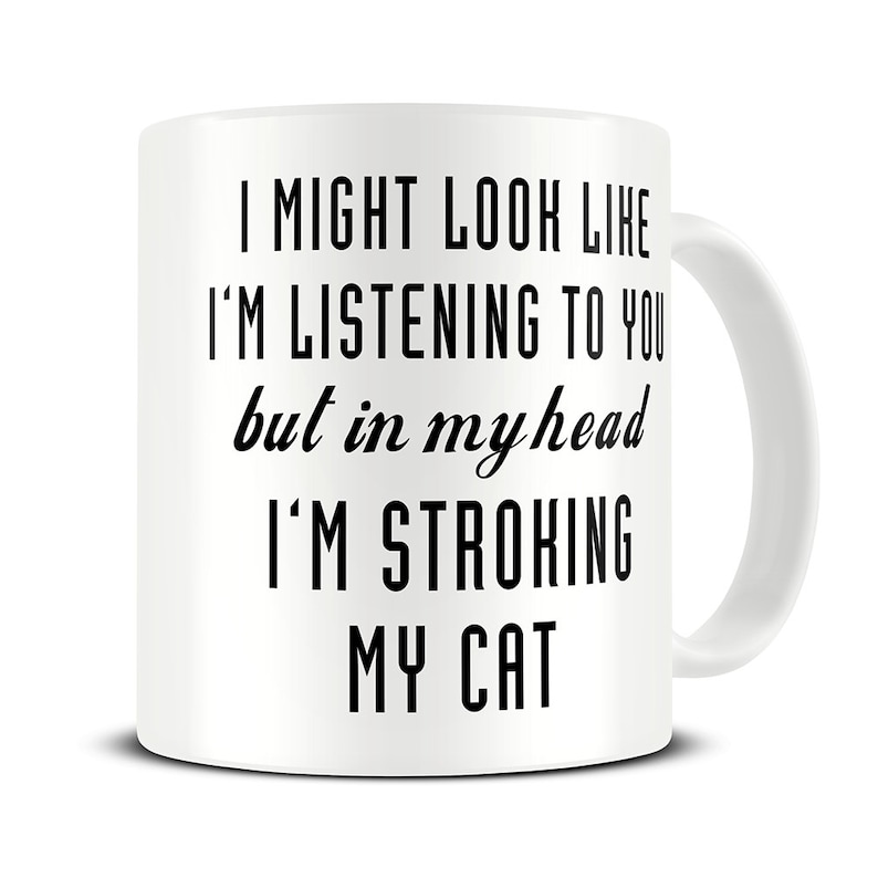 May include: White ceramic coffee mug with black text that reads "I might look like I'm listening to you but in my head I'm stroking my cat."