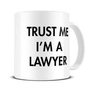 May include: White ceramic coffee mug with black text that reads "Trust me I'm a lawyer".