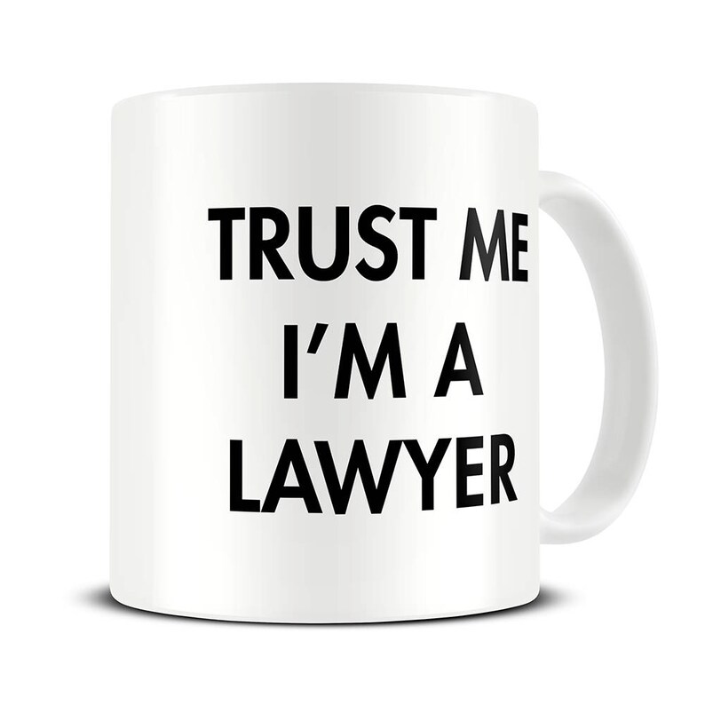 May include: White ceramic coffee mug with black text that reads "Trust me I'm a lawyer".
