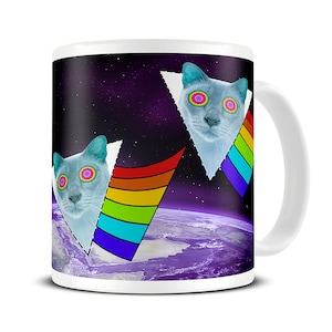 May include: White ceramic mug featuring a surreal design. The design includes two light blue cat faces with psychedelic eyes, set against a space background with a rainbow prism effect. The mug has a white handle.