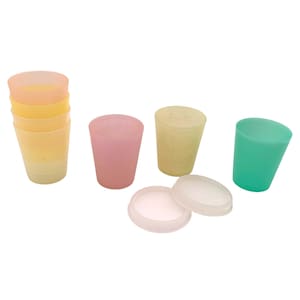 May include: A collection of small, translucent plastic cups in various pastel colors including yellow, pink, and green, alongside two circular, semi-transparent lids. The cups are arranged in a stack and individually, showing a matte finish.