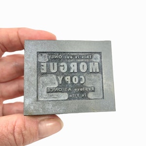 May include: A metal stamp with the text "Replace in file COPY A TONCE MORGUE This is our only"