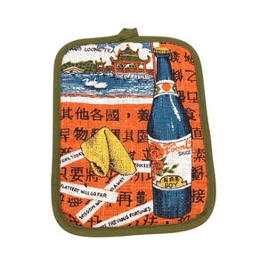 Pode incluir: Um descanso de panela retangular com borda verde. O design apresenta uma garrafa azul de "Loon Sauce" e um biscoito da sorte em um fundo laranja com caracteres chineses. Uma pagoda e cisnes também são retratados.