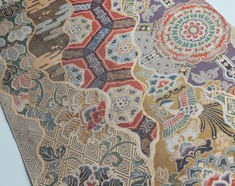 Pode incluir: Um close-up de um tecido dourado com um padrão complexo de flores, formas geométricas e pássaros. O tecido é tecido com uma variedade de cores, incluindo dourado, vermelho, azul, verde e roxo.