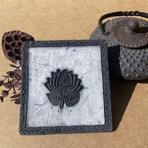 Raku ceramic trivet with black lotus flower motif. Place your dishes safely and brighten up your table