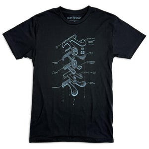 Może przedstawiać: Czarny t-shirt z jasnoniebieskim nadrukiem diagramu. Diagram jest techniczną ilustracją urządzenia mechanicznego, z etykietami i pomiarami. Koszulka ma logo Story Spark na g&oacute;rze.