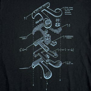 Może przedstawiać: Czarna koszulka z jasnoniebieskim schematycznym diagramem symbolu Pi, zawierającym wzory matematyczne i liczby. Tekst zawiera "Pi Day: March 14th". Projekt jest widokiem rozstrzelonym.