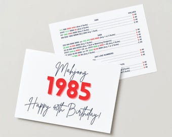 May include: A white card with a red and blue design. The card says "Mahjong 1985 Happy 40th Birthday!" and has a list of numbers and values. The card is a birthday card for someone who is turning 40.