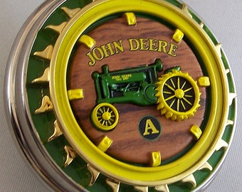 Peut inclure: Une montre de poche argentée avec un design de tracteur John Deere vert et jaune. Le tracteur est sur un fond en bois avec la lettre A dans un cercle.