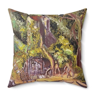 Pode incluir: Uma almofada com uma pintura de uma cena de floresta. A pintura apresenta uma pequena cabana, árvores e figuras em primeiro plano. As cores são principalmente verde, marrom e amarelo.