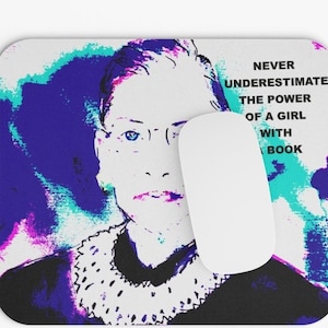 May include: A blue and purple mousepad with a digital art portrait of Ruth Bader Ginsburg. The text "Never underestimate the power of a girl with a book" is on the right side of the mousepad.