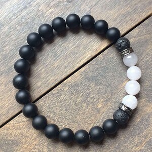 May include: A black and white beaded bracelet with black lava rock beads and white agate beads. The bracelet has silver metal accents.