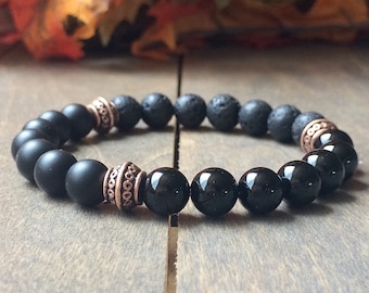 Puede incluir: Pulsera de cuentas negras con detalles en cobre. La pulsera presenta cuentas de lava negra y ónix.