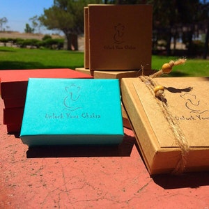 Two small boxes with the text "Unlock Your Chakra" on them. One box is teal blue and the other is brown. Both boxes have a small elephant symbol on them.