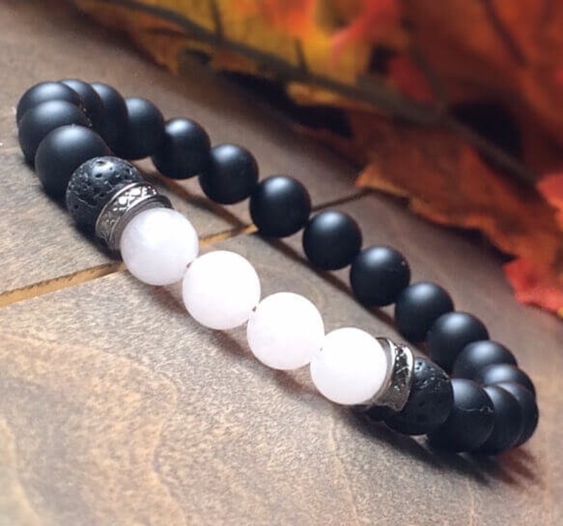 May include: A black and white beaded bracelet with a silver accent. The bracelet features black matte beads, white beads, and a silver spacer bead.