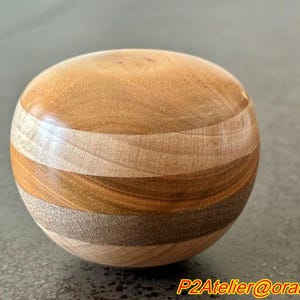 May include: A wooden sphere with a layered design, featuring alternating bands of light and dark wood.