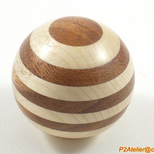 May include: A wooden sphere with alternating brown and white stripes. The sphere is made of two different types of wood, creating a unique pattern.