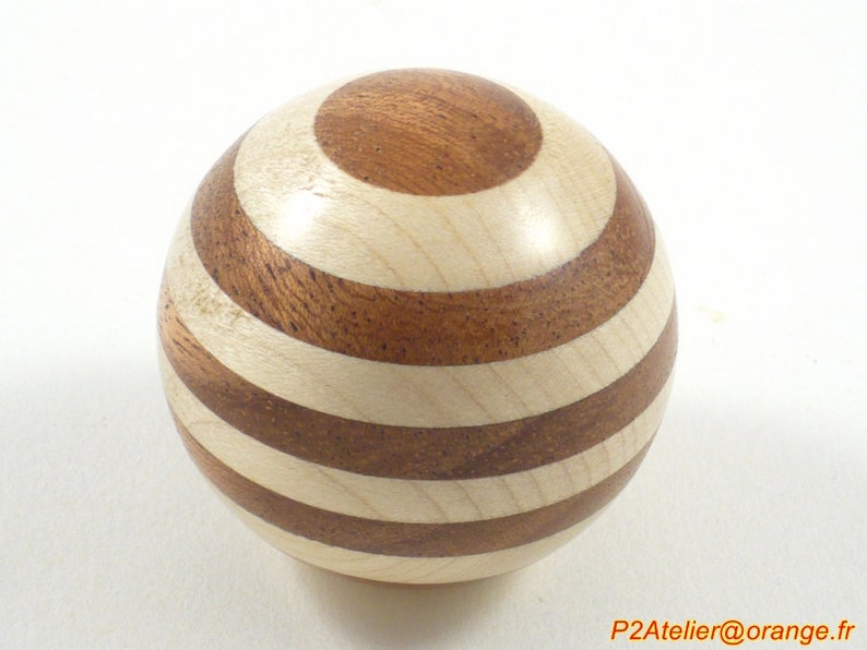 May include: A wooden sphere with alternating brown and white stripes. The sphere is made of two different types of wood, creating a unique pattern.