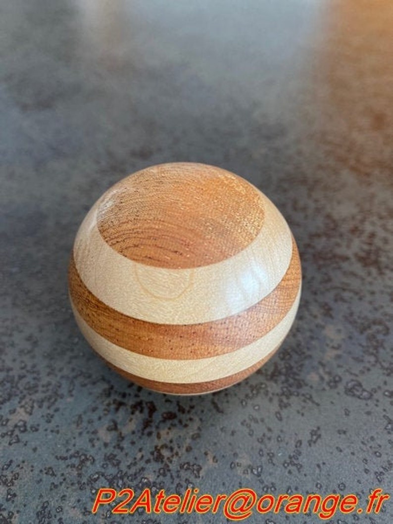 May include: A wooden sphere with alternating bands of light brown and white wood.