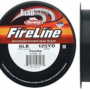 以下が含まれることがあります： 黒い FireLine マイクロフュージョンブレイドビーズスレッドフィッシングラインのスプール。スプールには、ブランド名、製品名、仕様（6lb テスト、125 ヤード、スモークカラーなど）が記載されています。