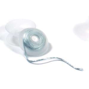 May include: A spool of light blue dental floss in a clear plastic dispenser. The floss is unwinding from the spool.