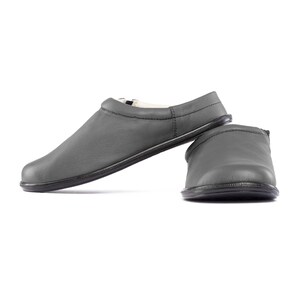 May include: A pair of gray leather slippers with a soft, comfortable lining. The slippers have a simple, classic design and are perfect for relaxing at home.